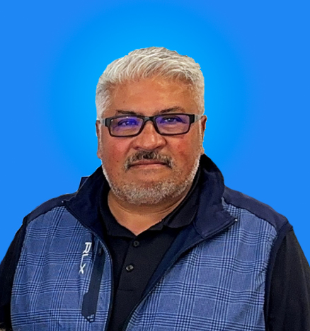 Portrait of a professional in the event industry with glasses, wearing a vest, smiling in front of a blue background.