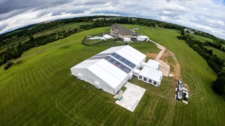 Aerial view of a large event tent installation with event flooring, tents, and structures on a grassy field.
