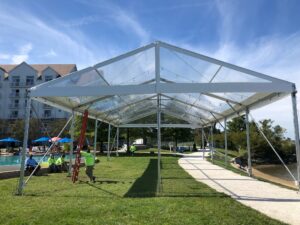 A frame tent setup with wooden flooring, ready for a refined outdoor event like a wedding or gala, providing both shelter and style.