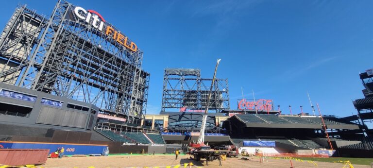 Wide stadium surface conversion zone using connected white turf protection panels, perimeter barriers, and forklift machine access, venue floor protection for heavy load distribution and non-sport event builds.
