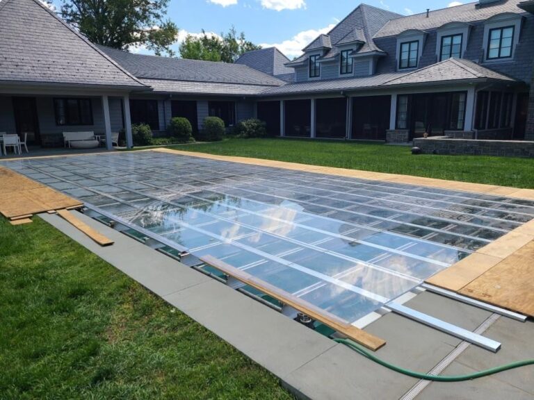 Clear event flooring installation in a courtyard, with large transparent panels being placed to create a surface for an outdoor event setup.