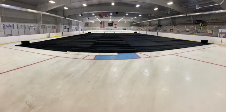 Indoor ice hockey rink with black turf protection rubber mats placed over ice, event conversion flooring system, ice cover and turf safeguarding for arena events.