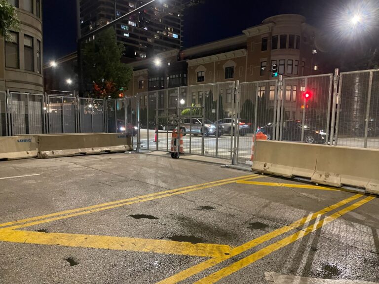 Anti-scale fencing setup with concrete barriers, securing an event area at night in an urban location.