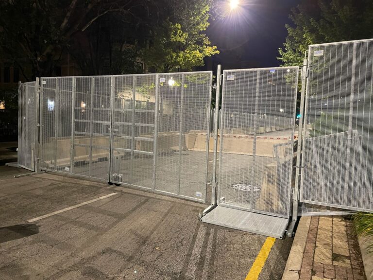 Event fencing setup for crowd control with a large gate for entry, ideal for securing areas at events such as festivals, concerts, or sporting events.