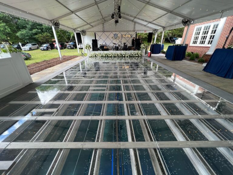 Outdoor wedding reception setup with a pool cover turned into an elegant dance floor, surrounded by floral decorations.