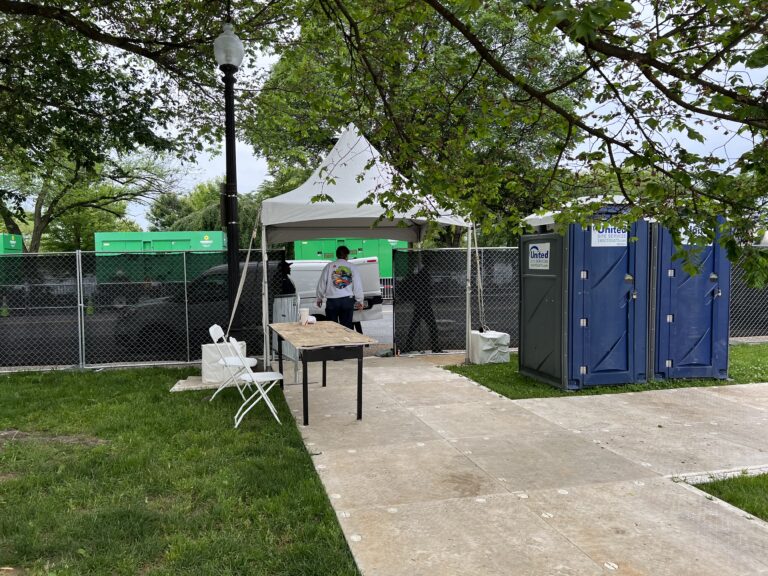 A fenced event area featuring portable toilets, a tent, and temporary infrastructure setup, creating an organized and secure environment for guests.