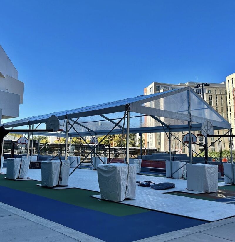 Event Flooring In Usa installed under a large outdoor event tent with sports flooring and protective covers in an urban setting.