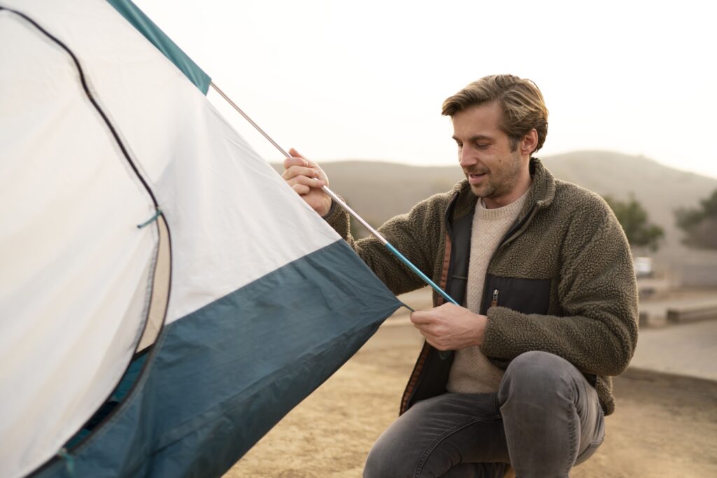 Camper secures a tent with Tents Stakes on dry ground, showing proper anchoring for wind-resistant outdoor camping