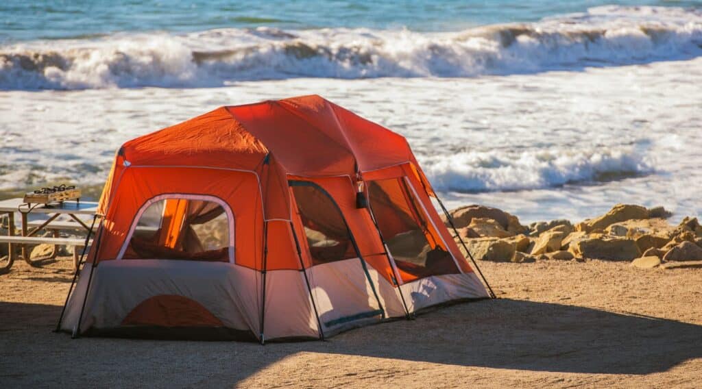 Instant tent set up on the beach with ocean waves in the background, ideal for quick outdoor escapes.