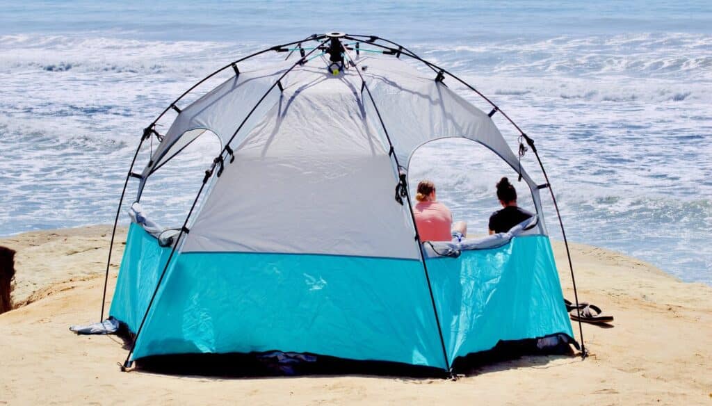 Neso tent set up on the beach, providing shade and comfort for a relaxing seaside experience.