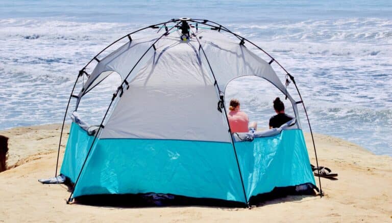 Neso tent set up on the beach, providing shade and comfort for a relaxing seaside experience.