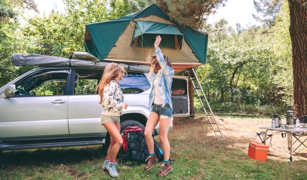 SUV tent setup next to a vehicle, providing shelter for outdoor camping and adventure.
