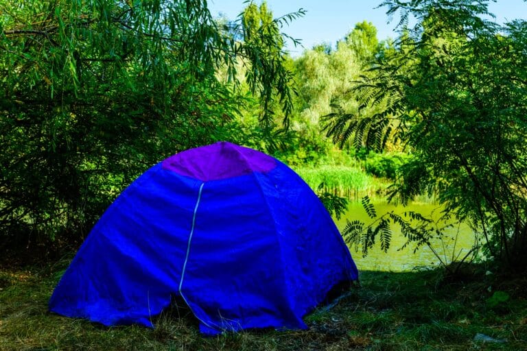 Relaxing sauna tent setup in nature by a calm lake, perfect for wellness and outdoor relaxation.