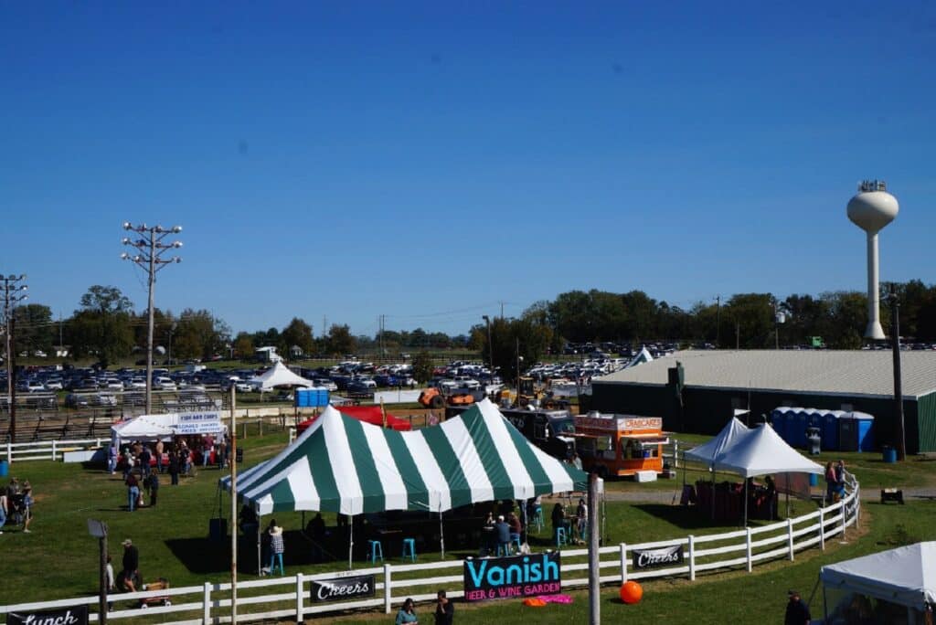 Large green and white striped custom printed tents set up at a busy outdoor event with food stalls and a beer garden.