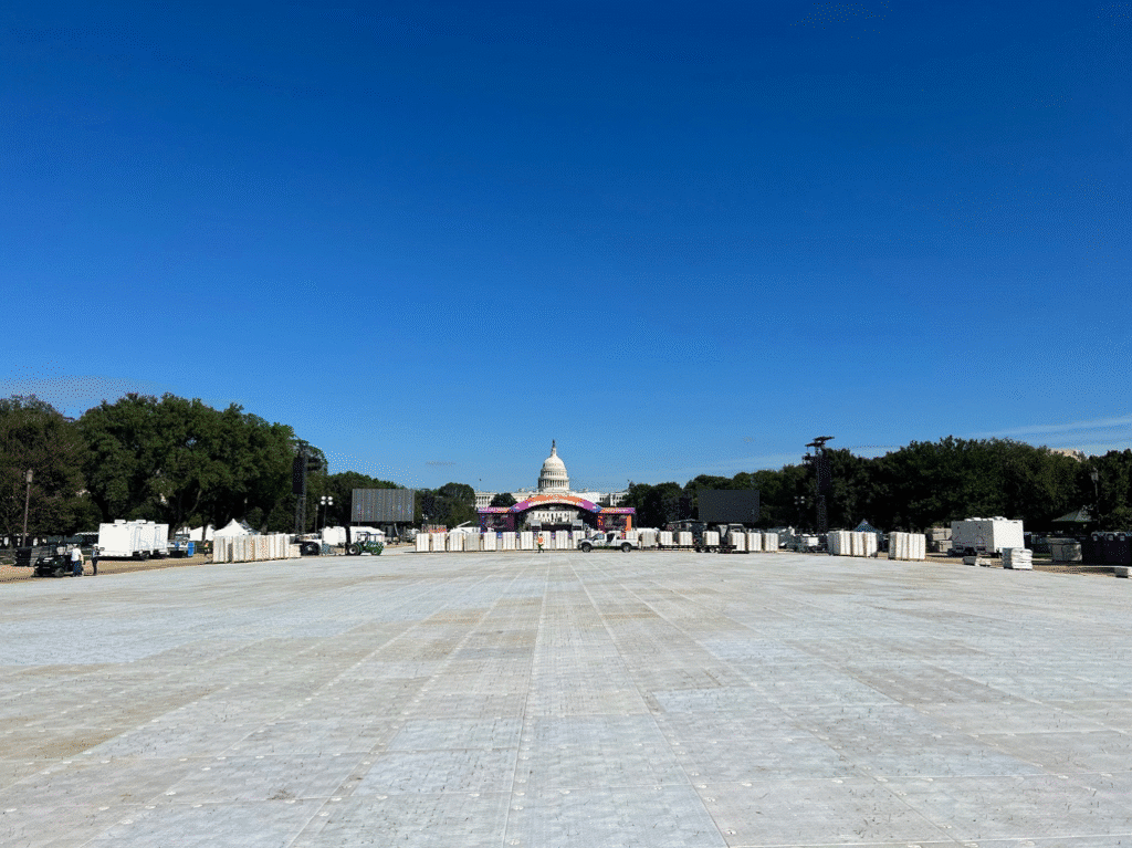 Large-scale installation of heavy-duty ground protection mats on a grass field in front of the U.S. Capitol for event site preparation.